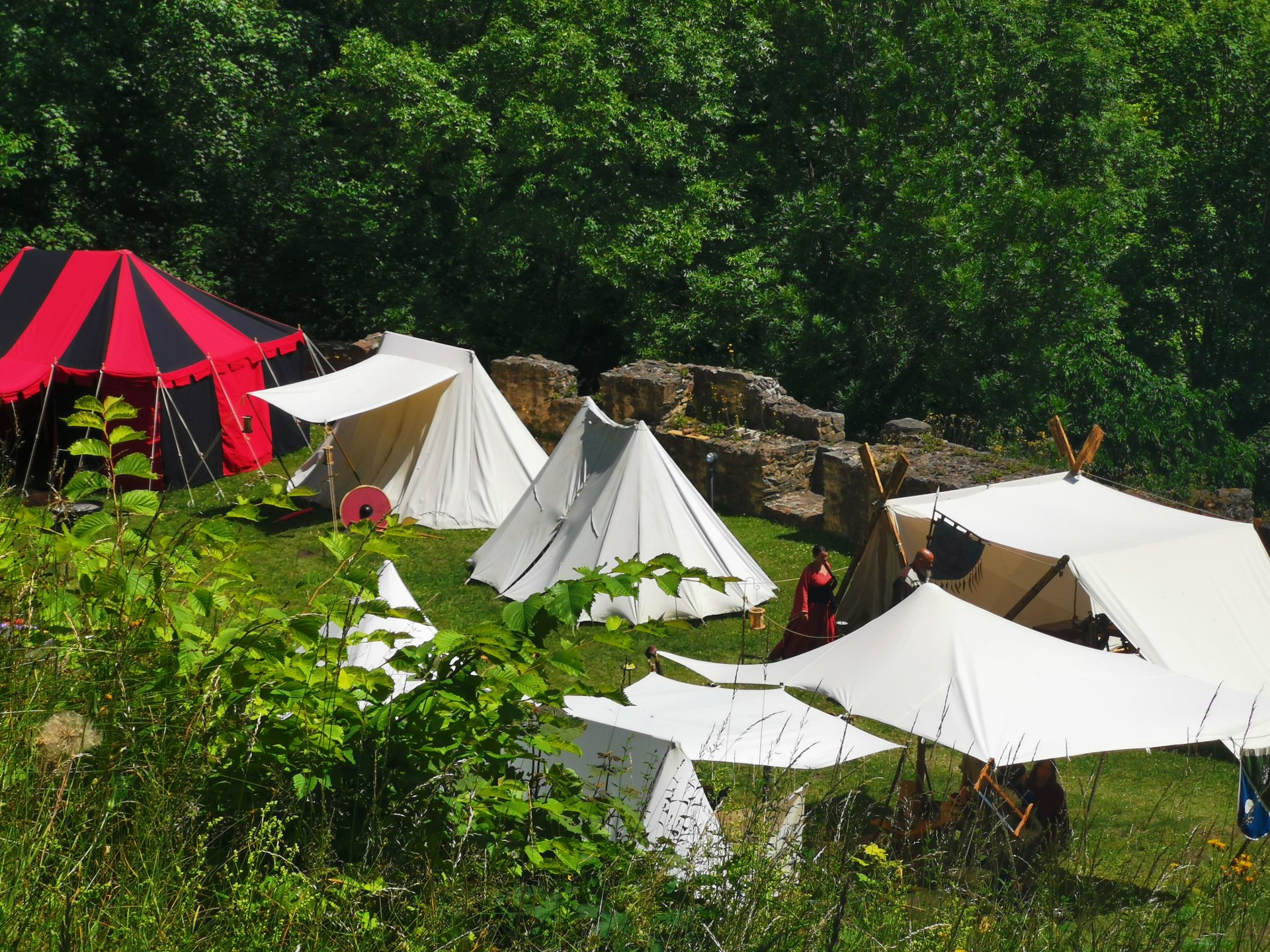 Mittelalterliches Lager mit weißen Zelten und rotem Turnierzelt auf dem Burggelände