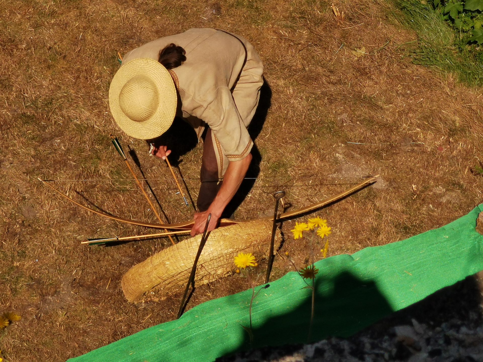 Darsteller mit Strohhut legt Bögen und Pfeile auf dem Boden zurecht